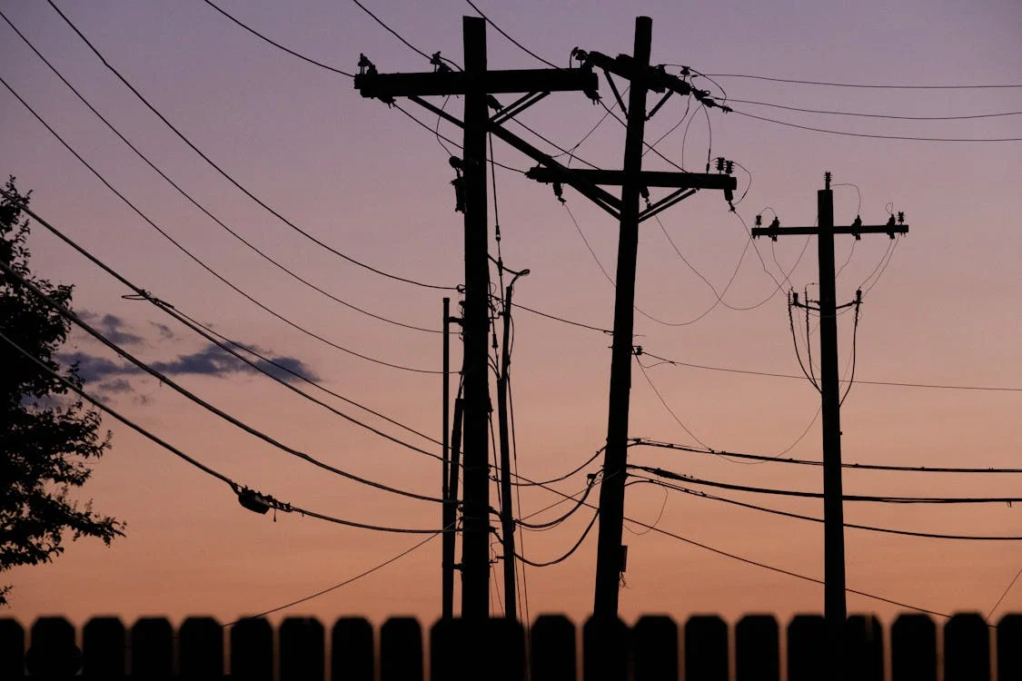 Silhoutte of electric posts during the sunsets, representing the sale of electricity back to the grid