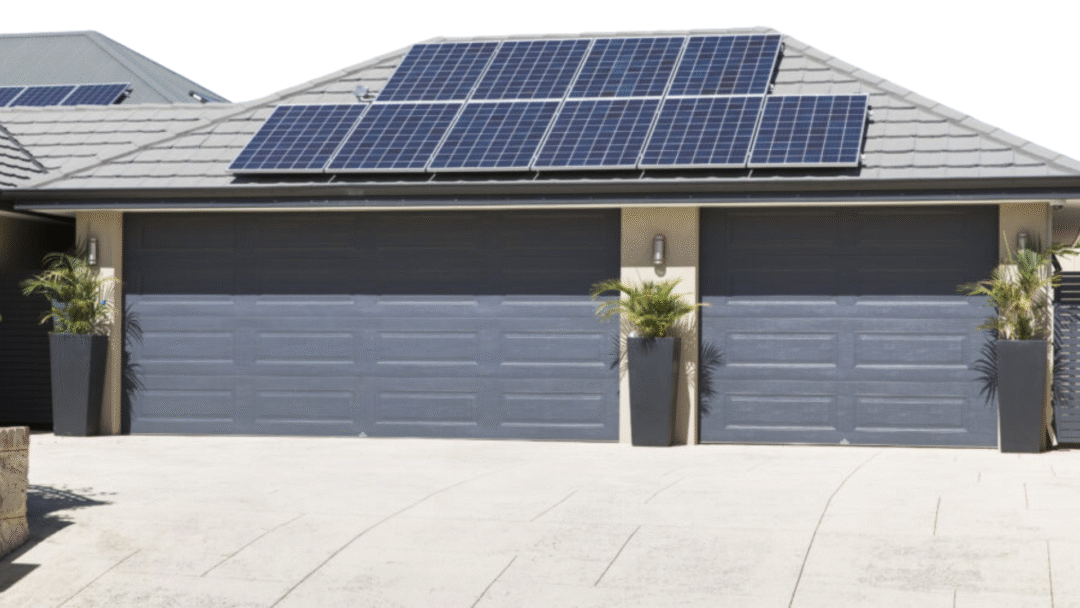 Solar panels installed on the tiled roof of a modern home with double garage doors.