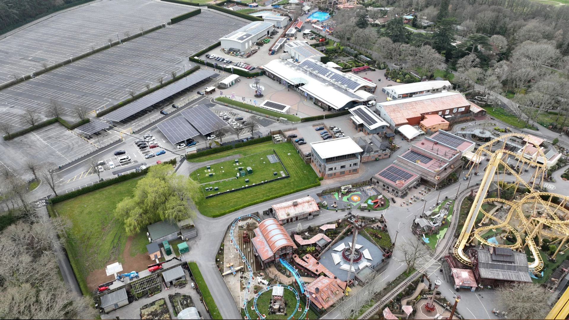 Aerial view of a theme park with solar panel rooftops and carports, showcasing large-scale use of renewable technologies.
