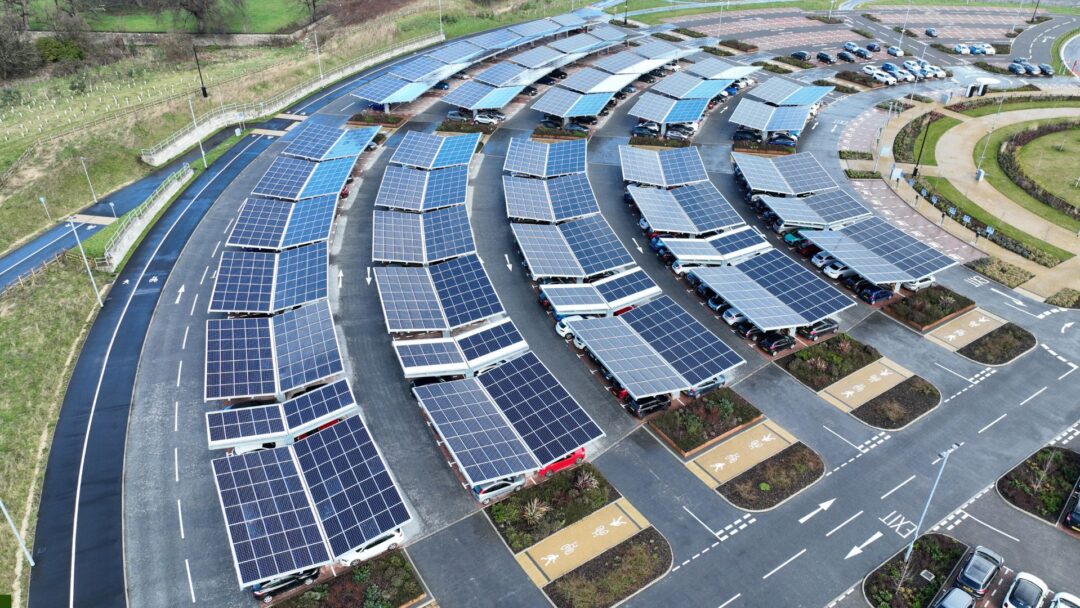 Large commercial parking lot covered by curved solar carports, providing renewable energy generation and shelter for numerous parked vehicles in Our ESG Report
