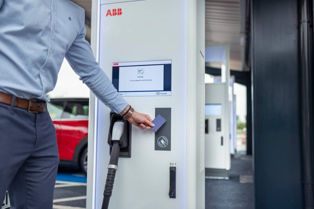 Customer tapping a payment card on a high-speed ABB Terra or Aura electric vehicle charging station to initiate a charge session in EV Charging
