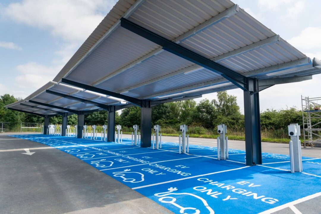 View of a dedicated EV Charging Only parking area under a protective canopy structure, featuring bright blue painted spaces and multiple charging posts in Solar Carports