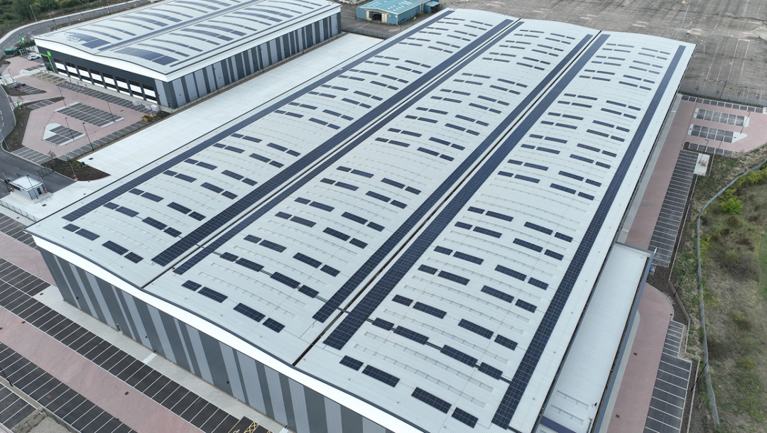 Multiple large commercial warehouses with rooftop solar panels installed across wide roof spans for business energy generation