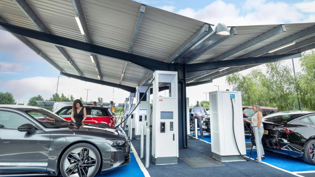 Electric vehicle drivers charging their cars under a covered solar carport equipped with multiple fast EV charging stations in Why Evo