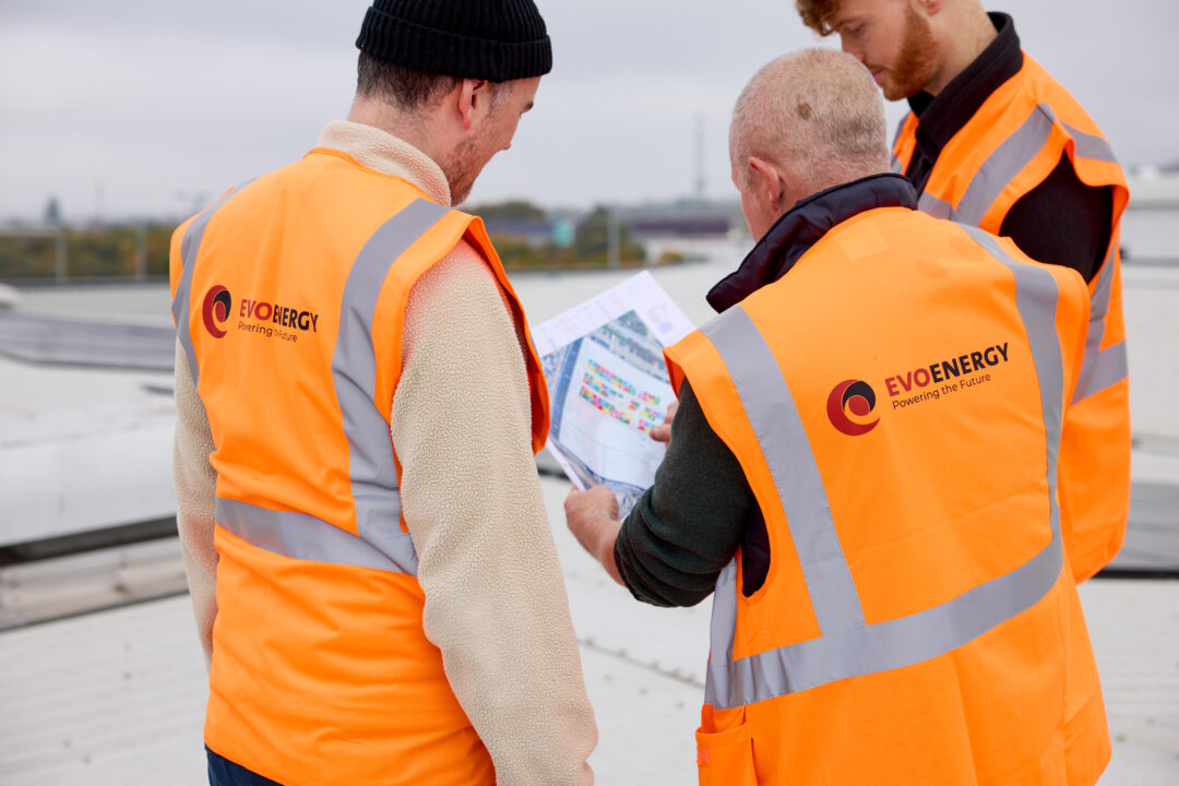 EvoEnergy team members reviewing a rooftop solar panel layout plan during a commercial installation project.
