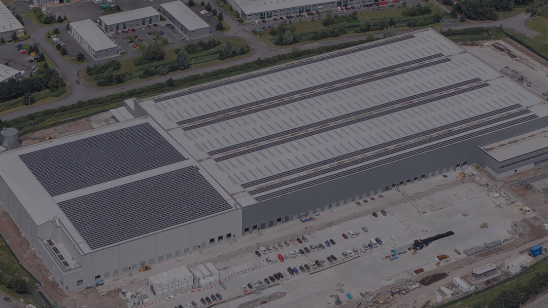 Aerial view of a large commercial building with extensive rooftop solar panel installation.