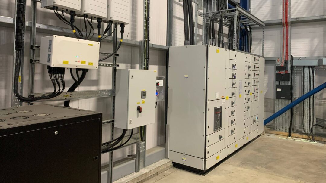 Indoor electrical room featuring solar PV system components including inverters, control panels, and power distribution units for a commercial renewable energy setup in DPD Docklands