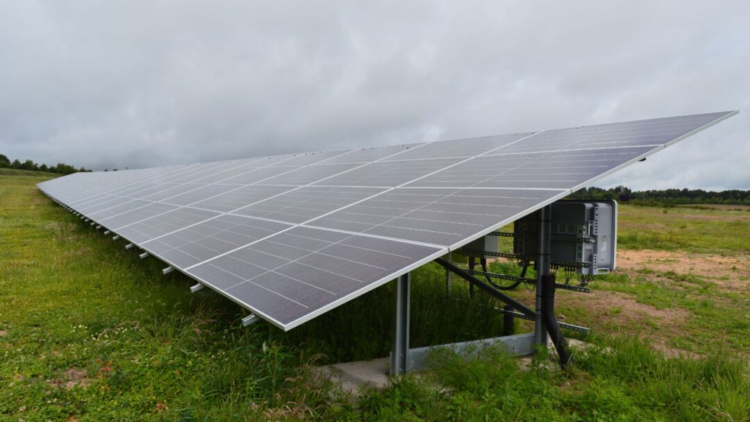Ground-mounted solar panel array in a rural field with integrated inverter components visible beneath the structure, used for generating renewable solar energy in Mansfield Sand.