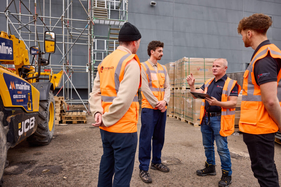 EvoEnergy team members discussing commercial solar installation work on an active construction site.