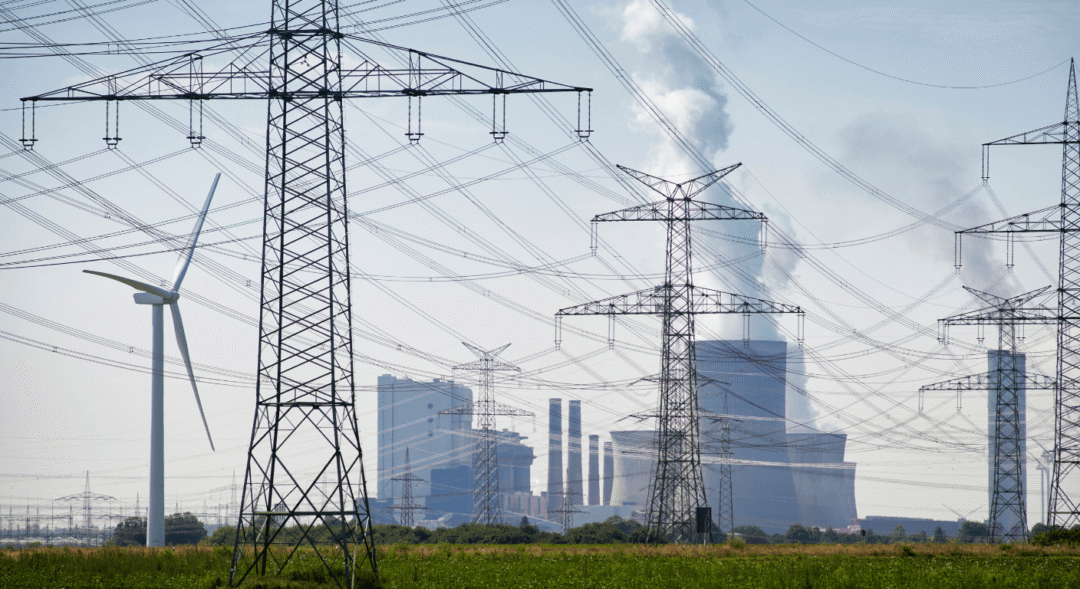 Electricity pylons, power station and wind turbine illustrating decentralised energy within a modern power network.