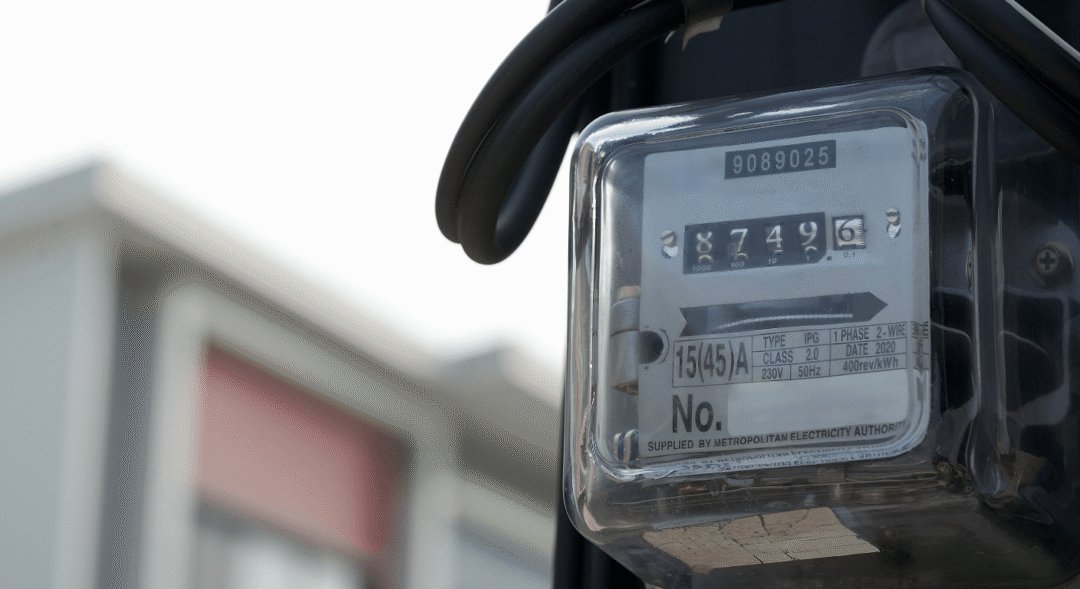 Close-up of an analogue electricity meter measuring residential electricity supply inside a transparent protective casing.
